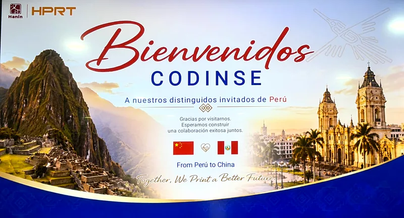 Pantalla de bienvenida de HPRT a la delegación peruana, con Machu Picchu y la Plaza de Armas de Lima