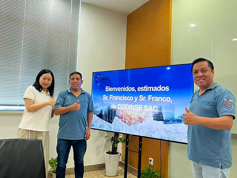 El equipo de CODINPE junto a una representante de UKCM frente a la pantalla de bienvenida